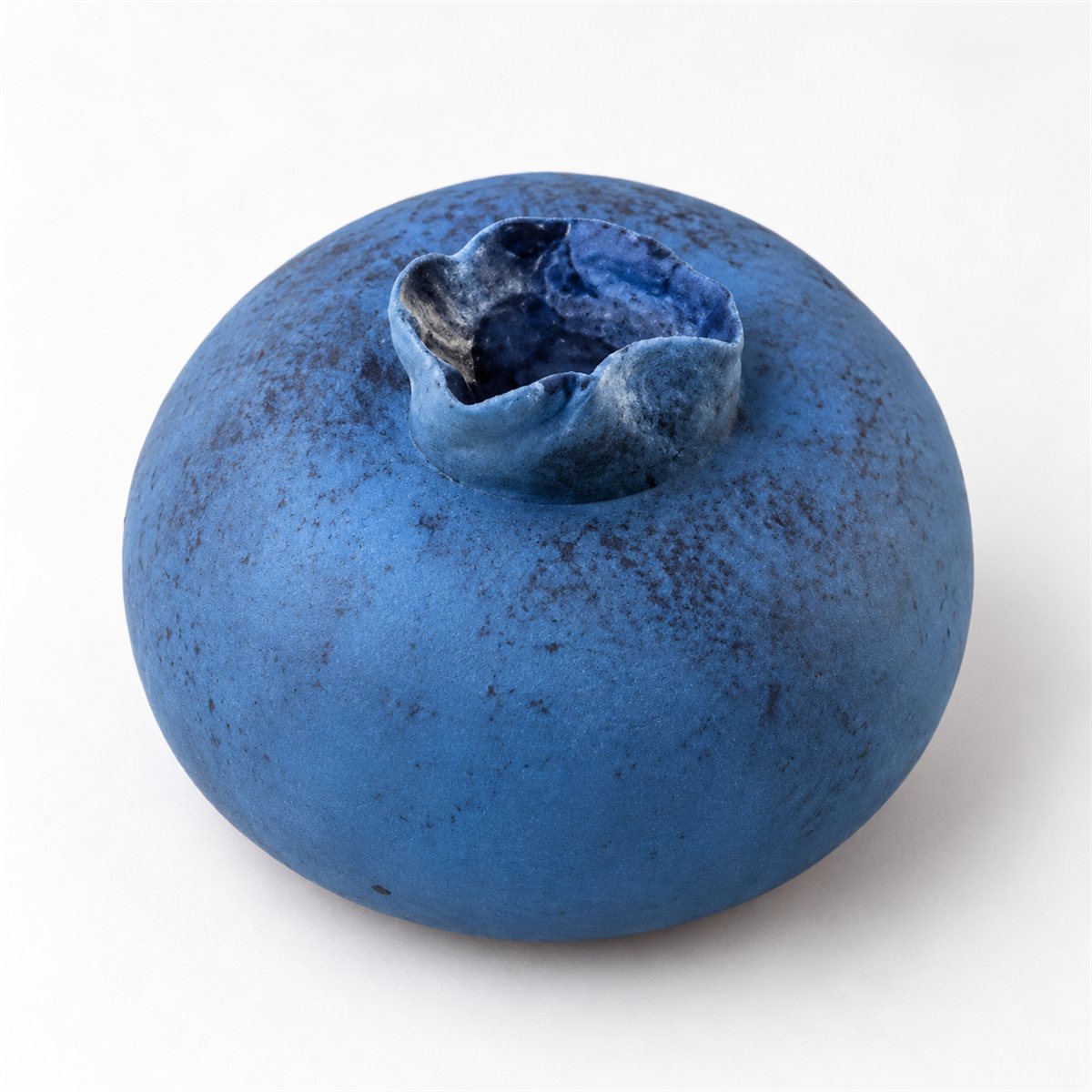 A round blue blueberry-design pie with a small dark-blue crown, photographed on white.