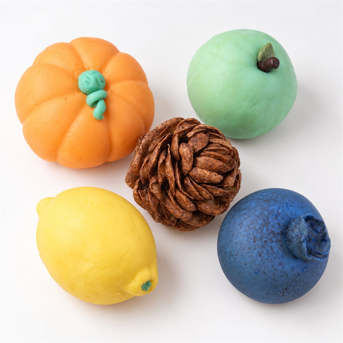 Sculpted pies shaped like a pumpkin, an apple, a lemon and a blueberry, with a pinecone